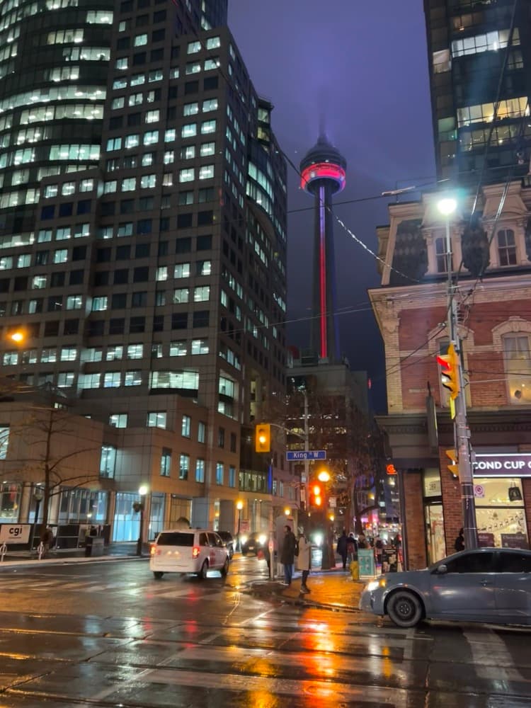 The CN Tower over a wet downtown street at night